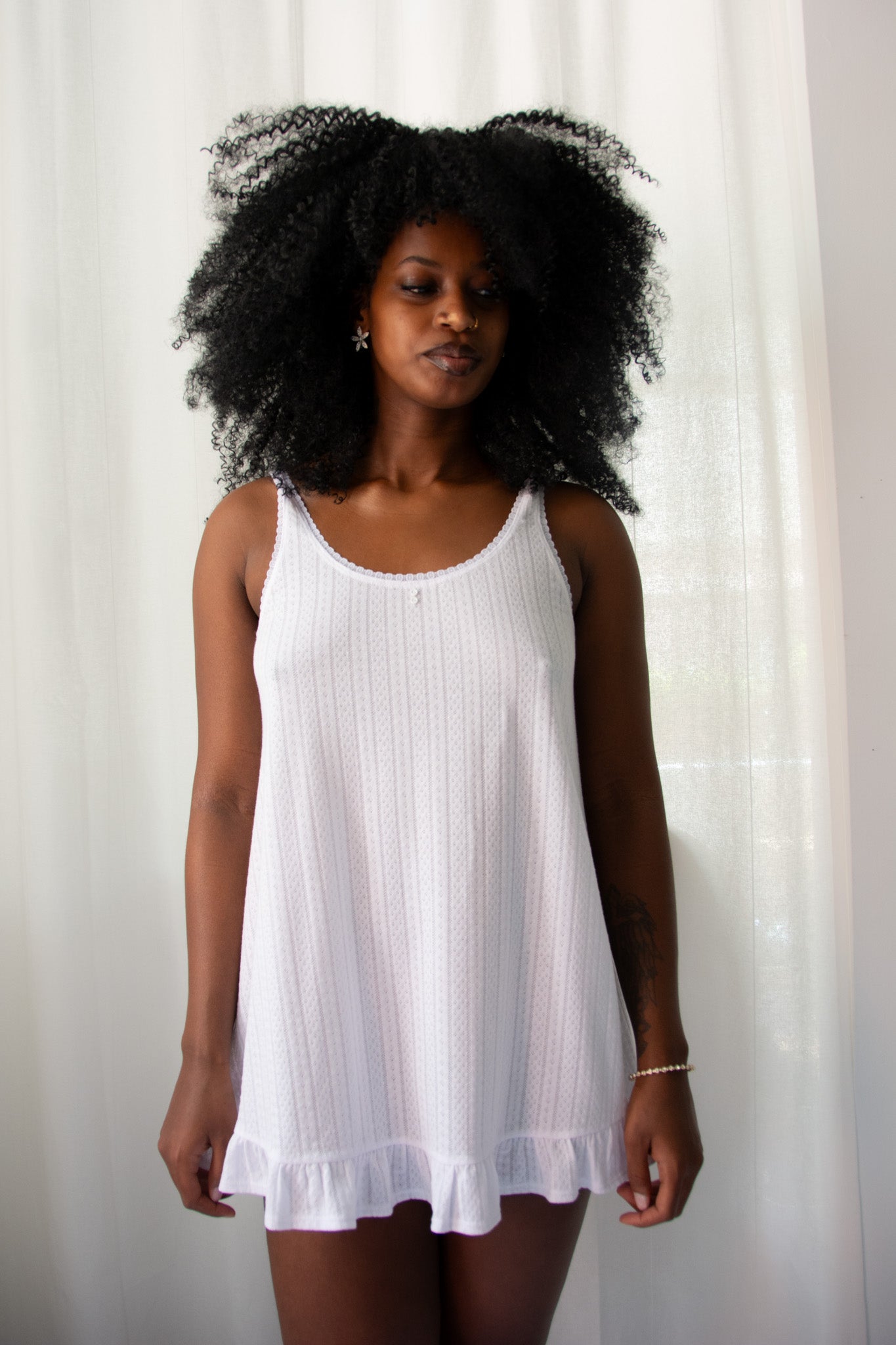 Woman wearing a white sleeveless dress against a plain background