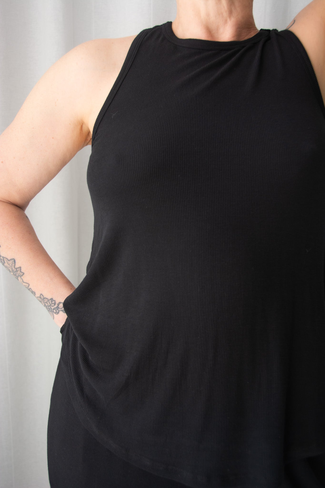 Person wearing a black sleeveless top against a light background