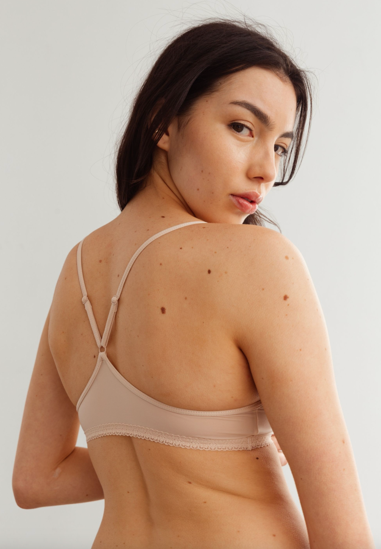 person wearing beige bralette against a white background 