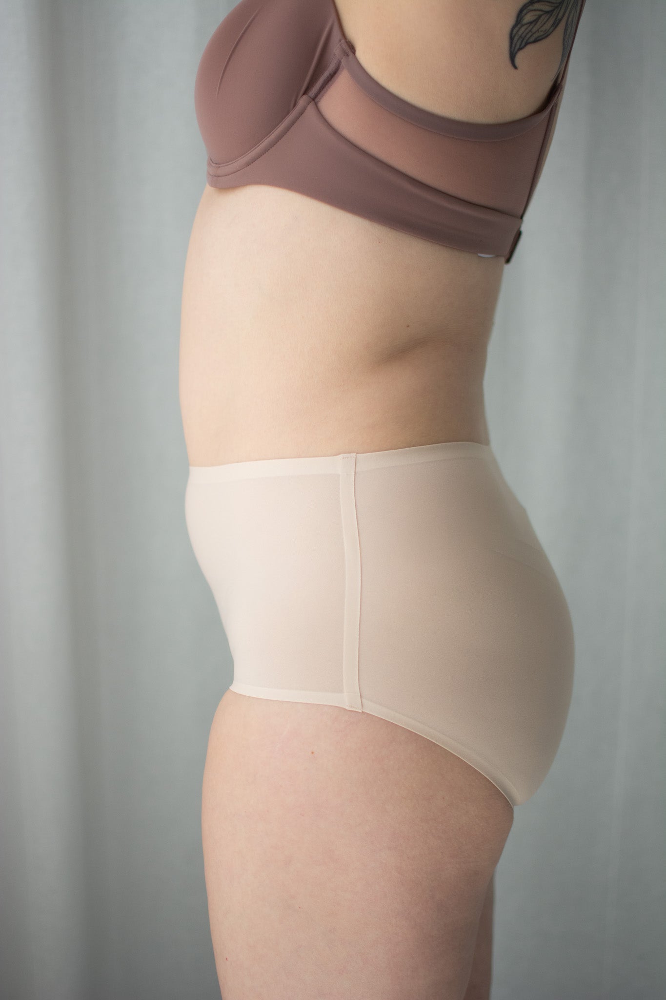 Person wearing a beige shapewear garment against a plain background