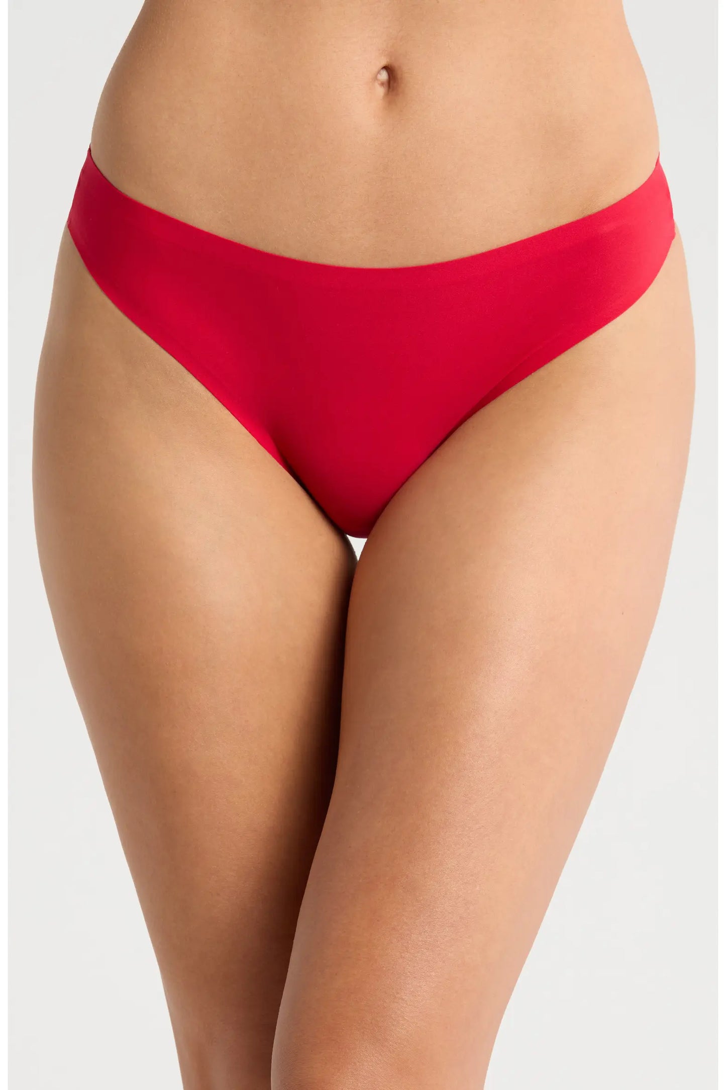 A close-up of a model wearing bright red bikini-style underwear against a light gray studio background.