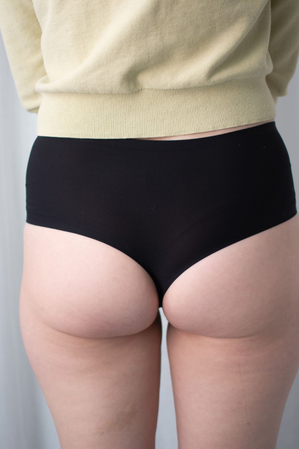 Chantelle soft stretch high waist thong in black, back view on a model, close-up.