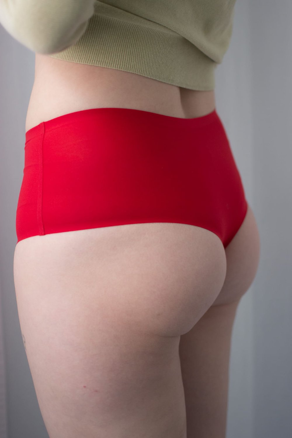 Chantelle soft stretch high waist thong in poppy red, back view on a model, standing at an angle, close-up.