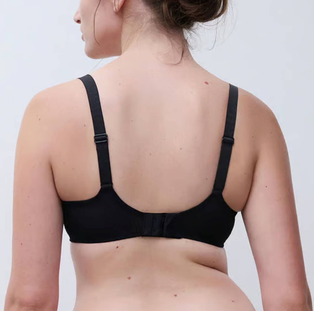 Black bra worn by a person on a plain background