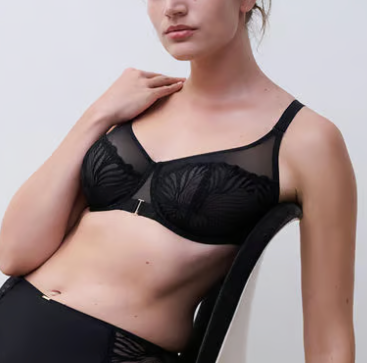 Woman wearing a black bra and underwear set against a plain background