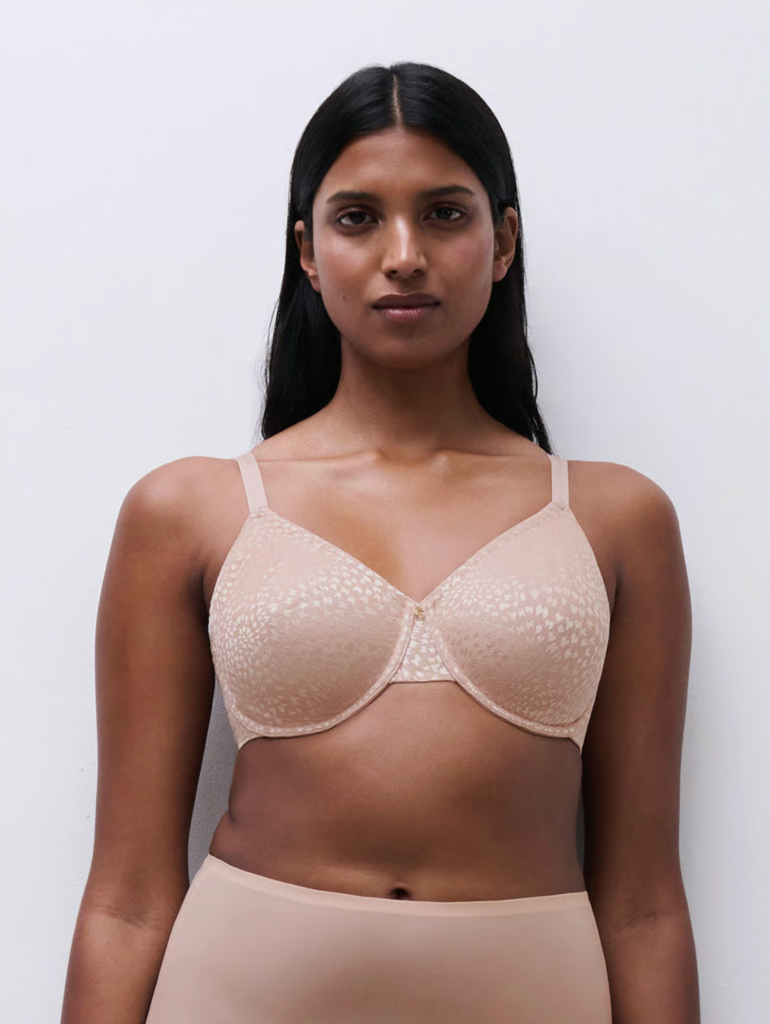 Woman wearing a beige bra against a plain background