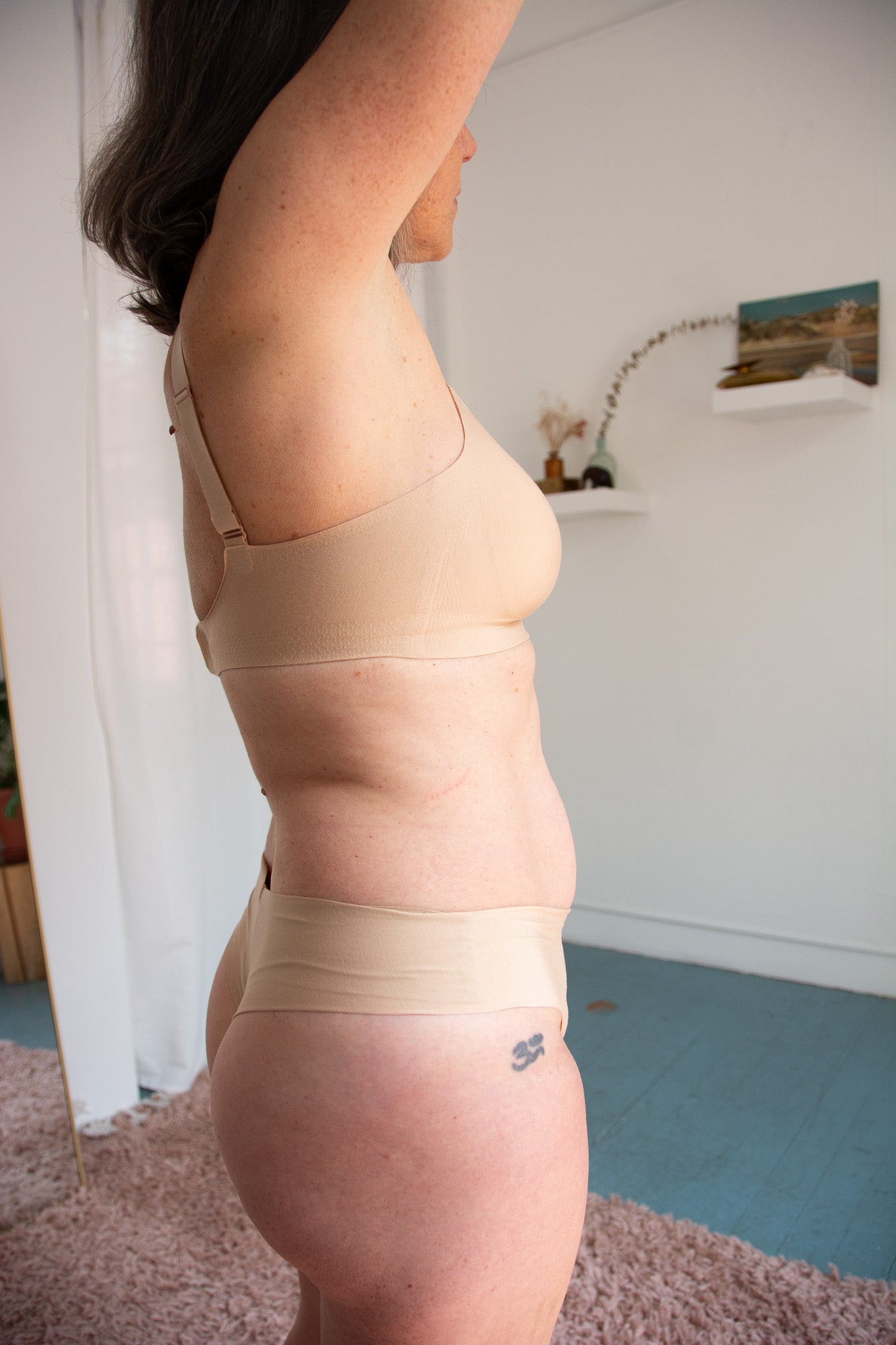 Person wearing beige bra and underwear in a room.