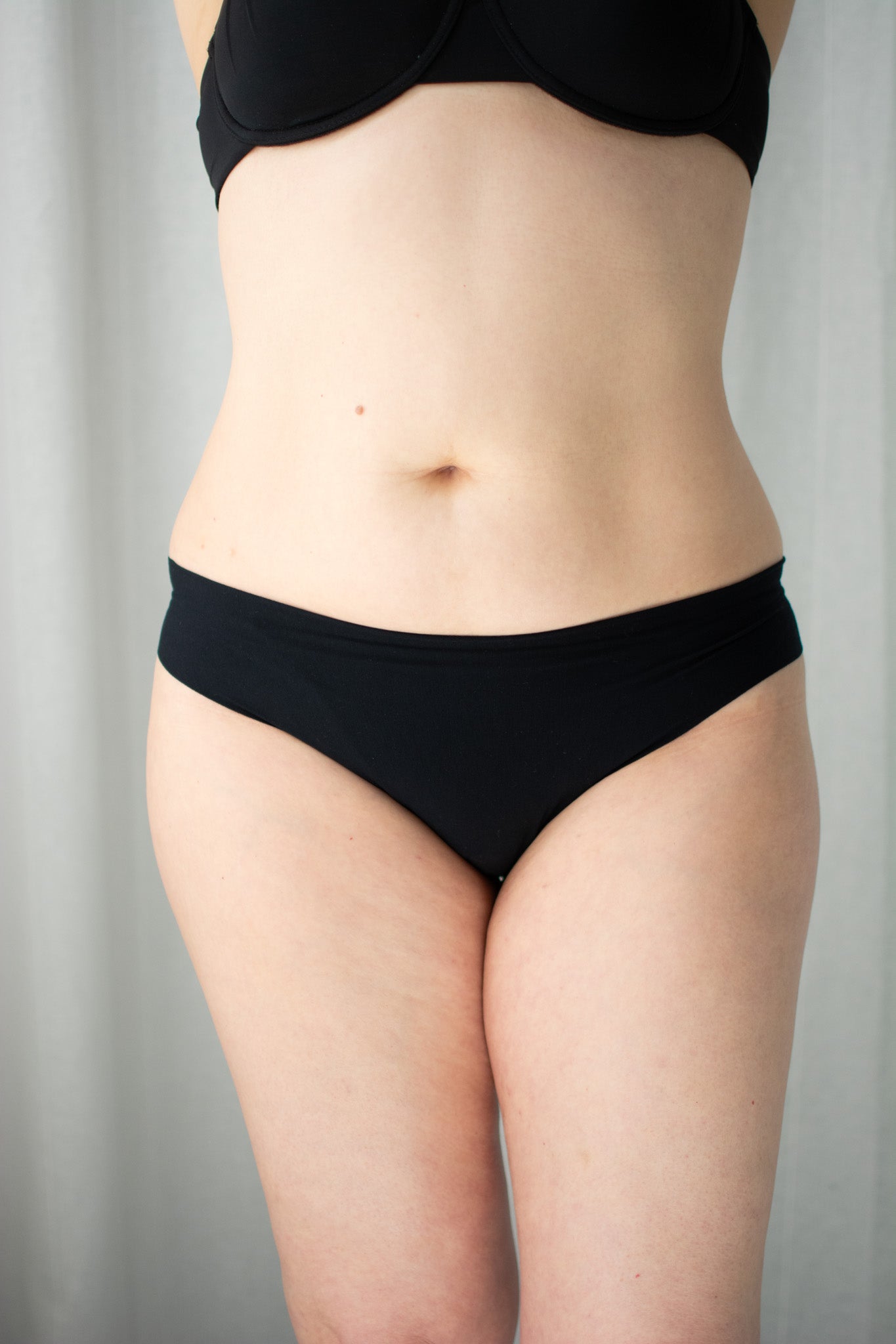 Person wearing black underwear against a neutral background