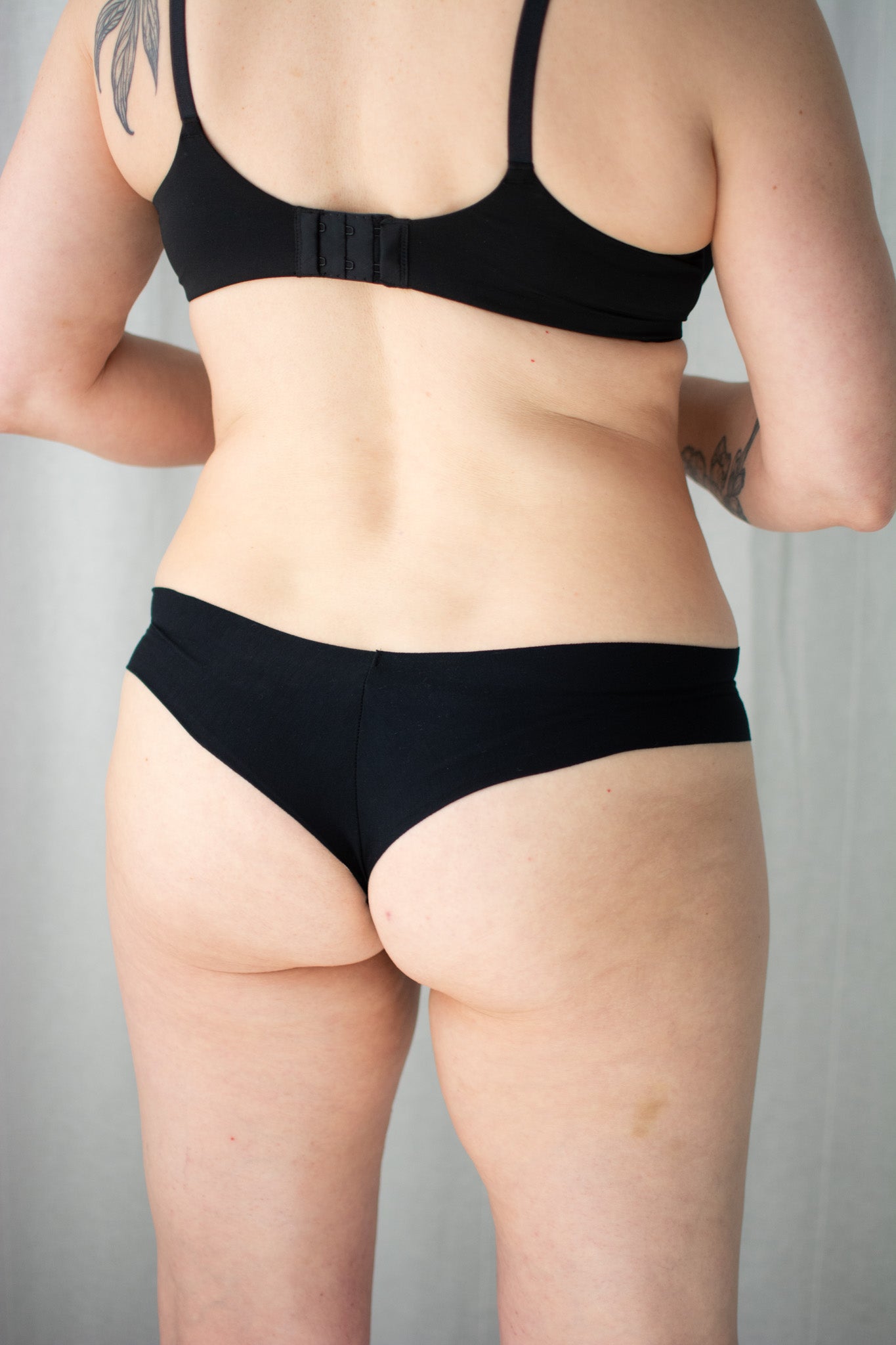 Person wearing a black bra and underwear set on a plain background