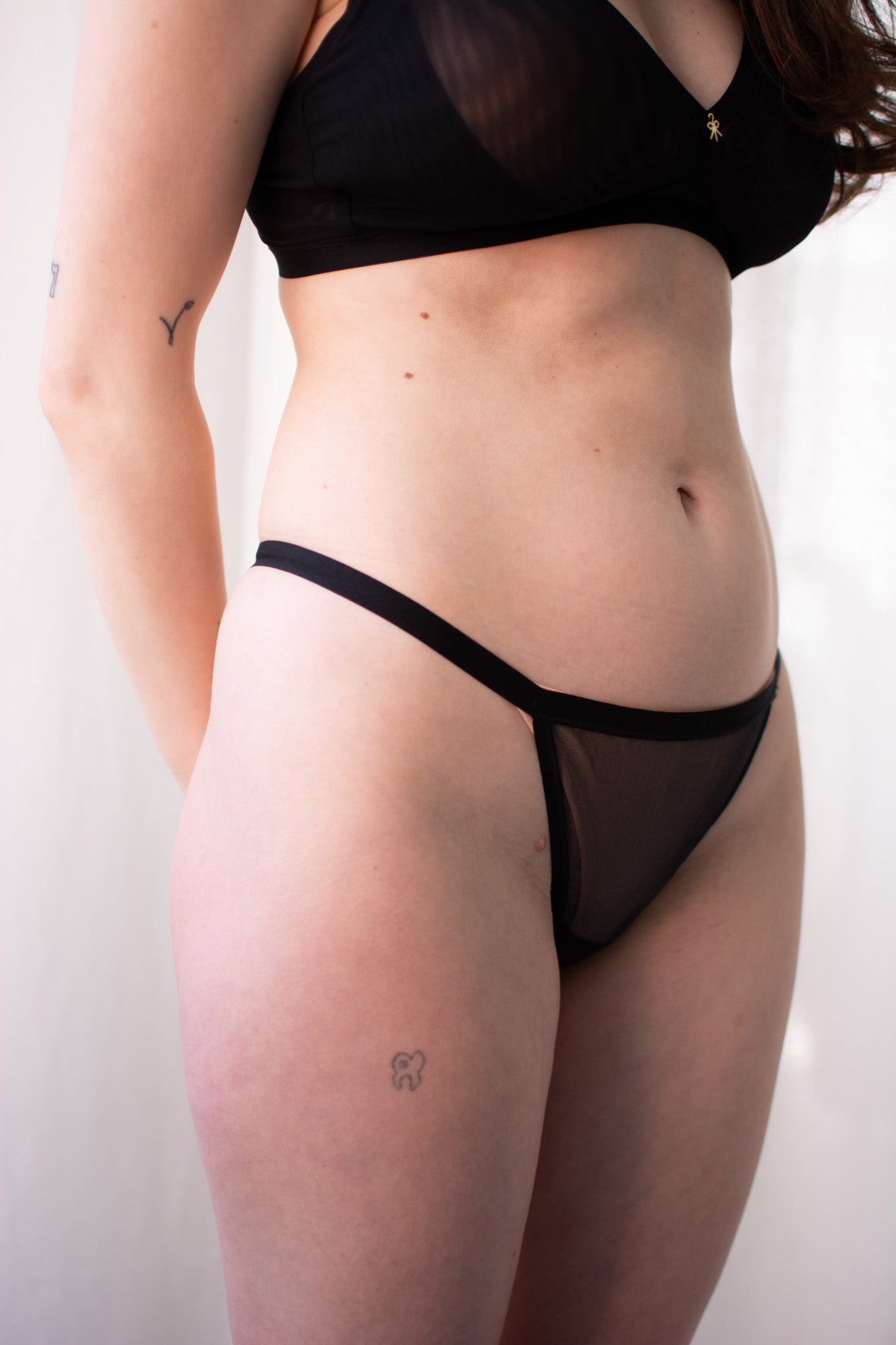 Person wearing black lingerie against a plain background