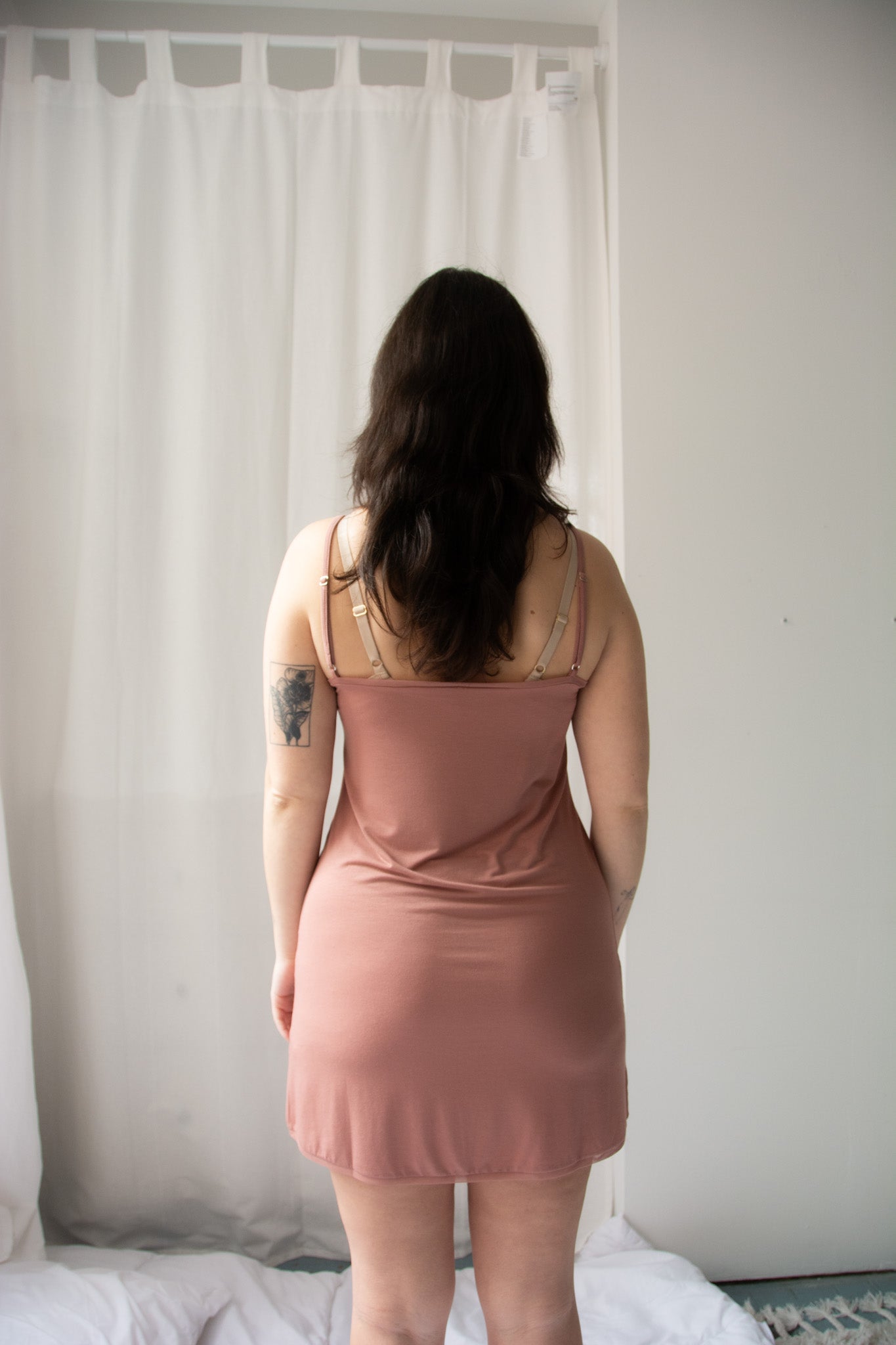 person from the back wearing a dusty rose chemise against a neutral background.