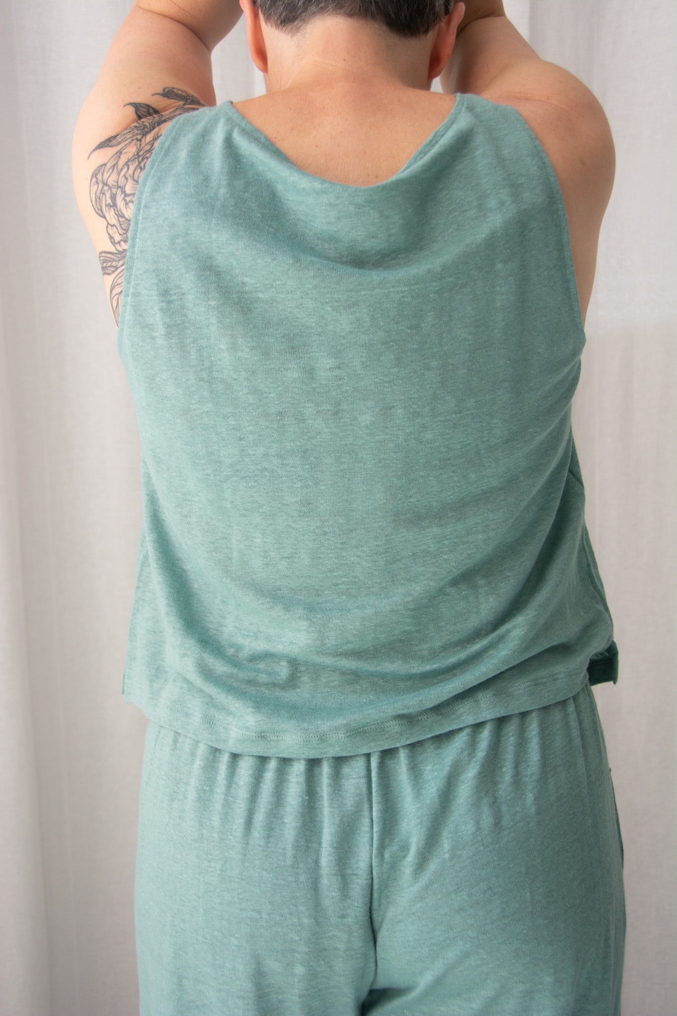 Person wearing a teal tank top and shorts set against a plain background
