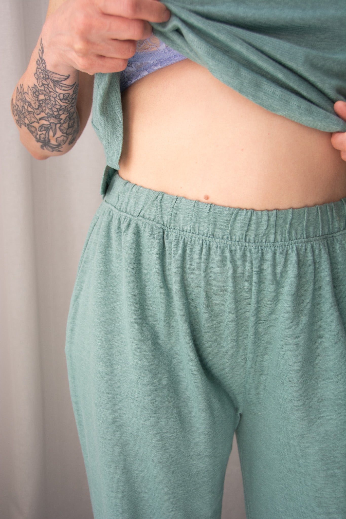 Person wearing teal pants with a neutral background