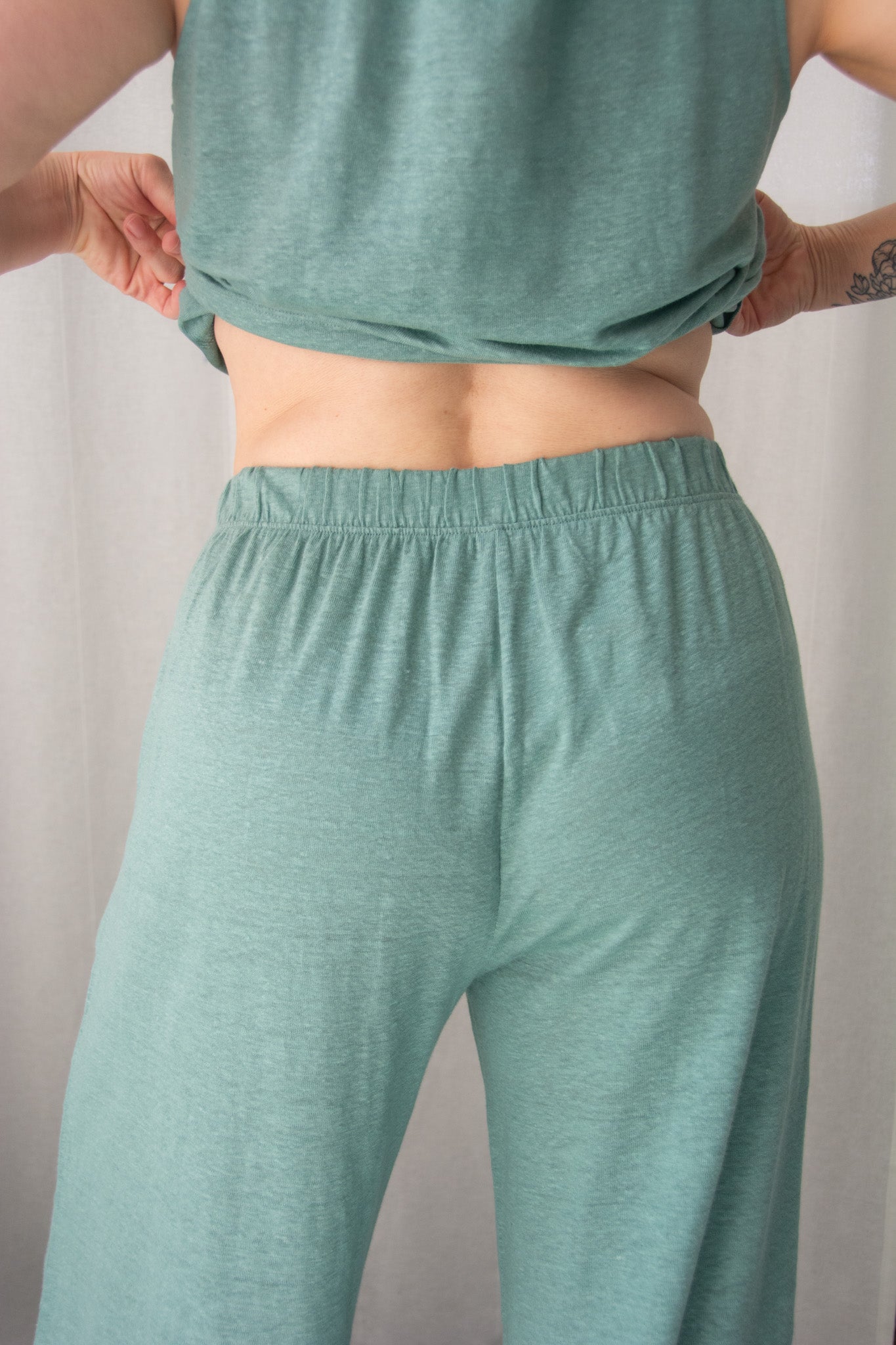 Person wearing teal athletic pants and a matching top against a plain background
