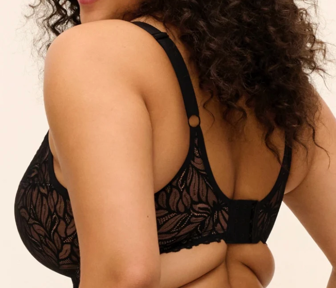 back of model wearing a black lace bra against a white background.