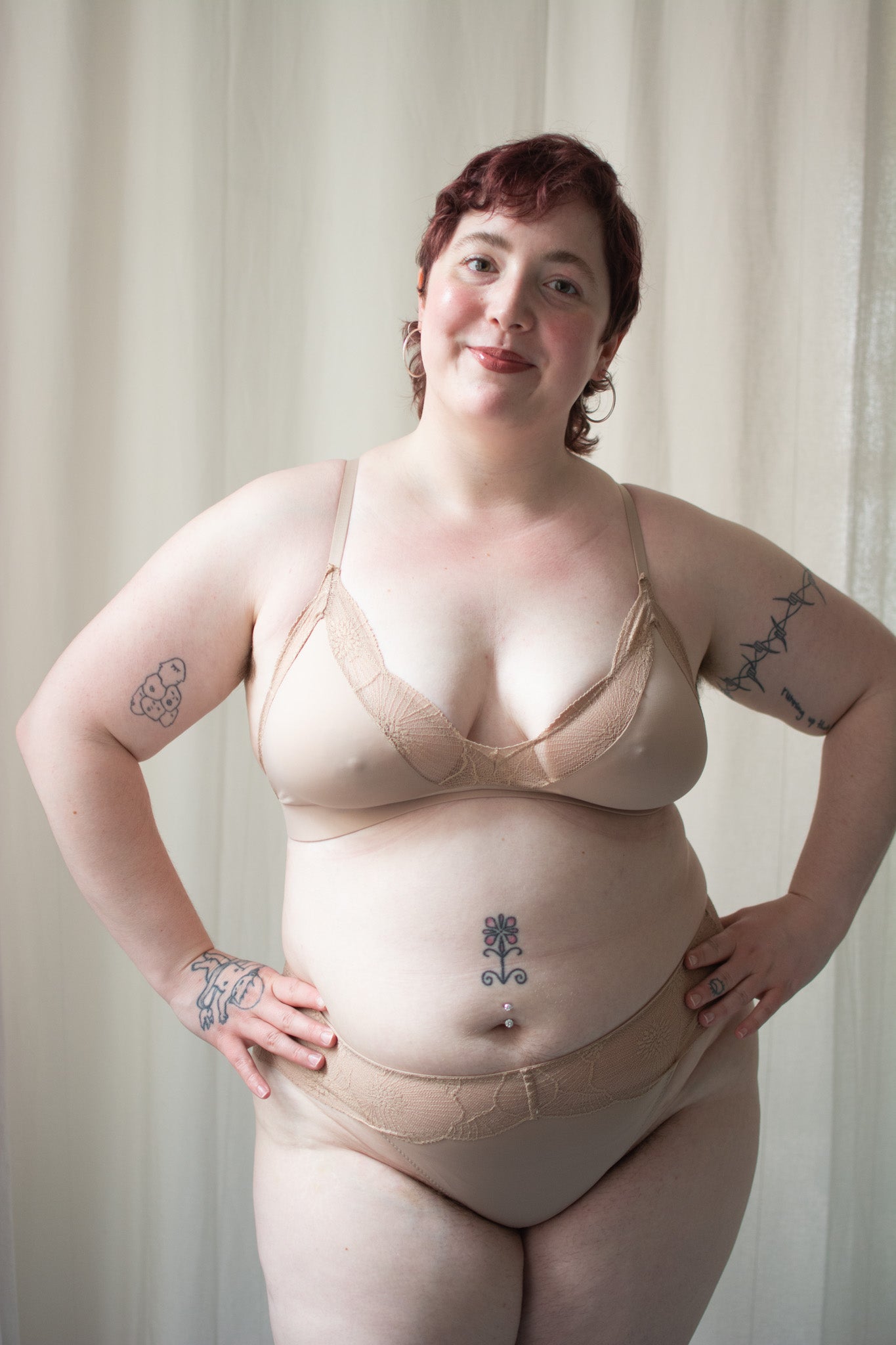 Person wearing beige lace bra and underwear against a neutral background.