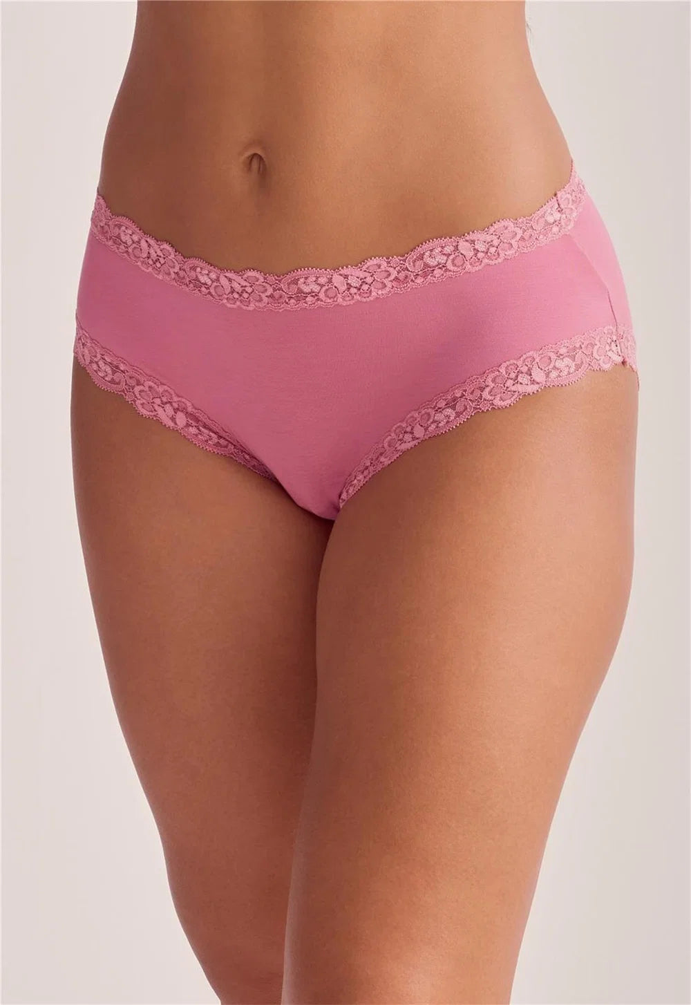 Pink women's underwear with floral lace trim, shown on a model against a light beige studio background.