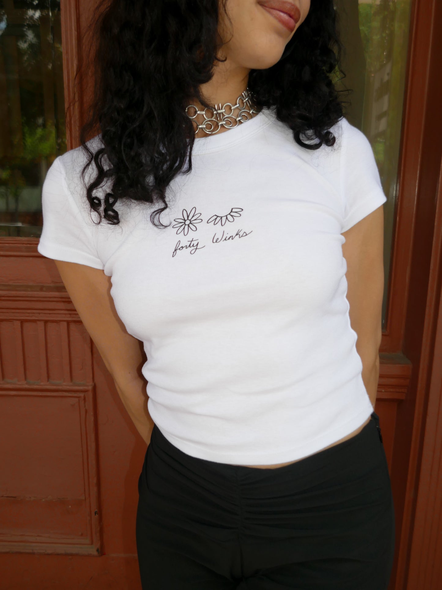 Person wearing a white t-shirt with text and graphics, standing indoors.