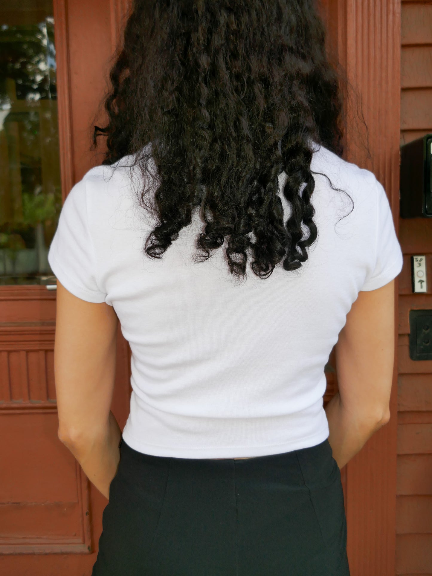 Person wearing a white blouse with a red door in the background