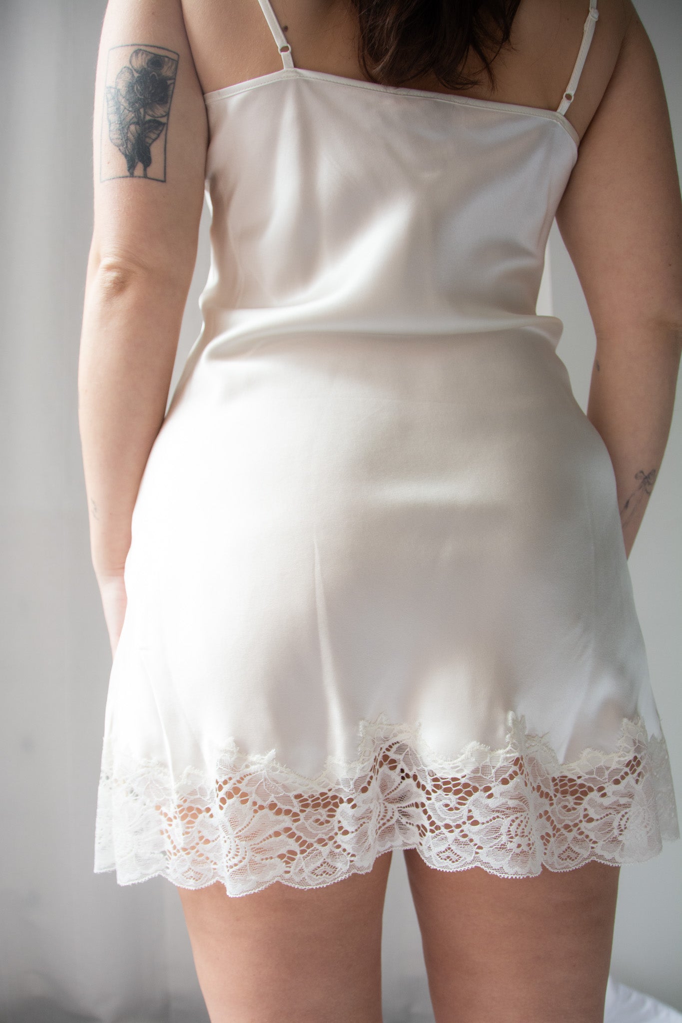 person wearing white silk chemise with lace trim against a white background