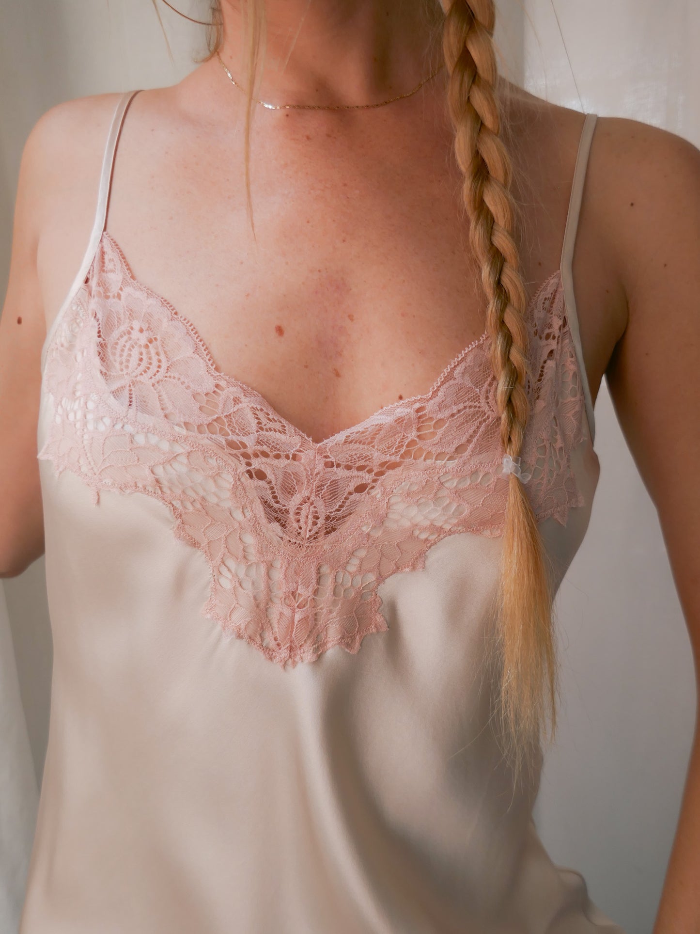 Woman wearing a lace-trimmed satin nightgown with a plain background