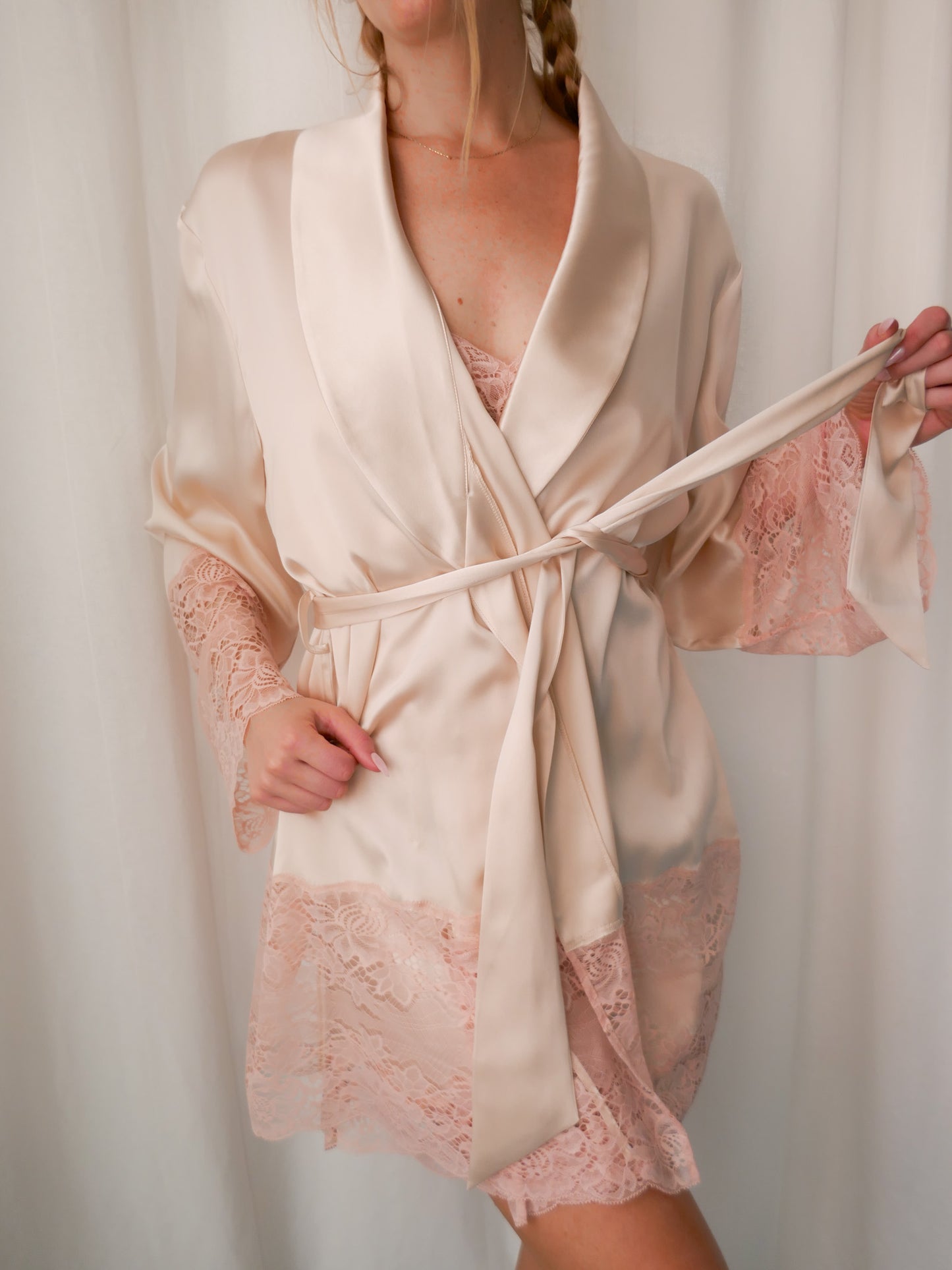 Beige robe with lace trim worn by a person against a white background