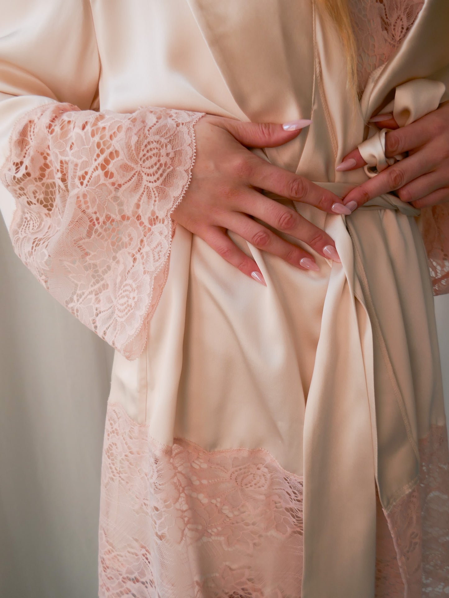 Close-up of a person wearing a beige lace-trimmed robe.