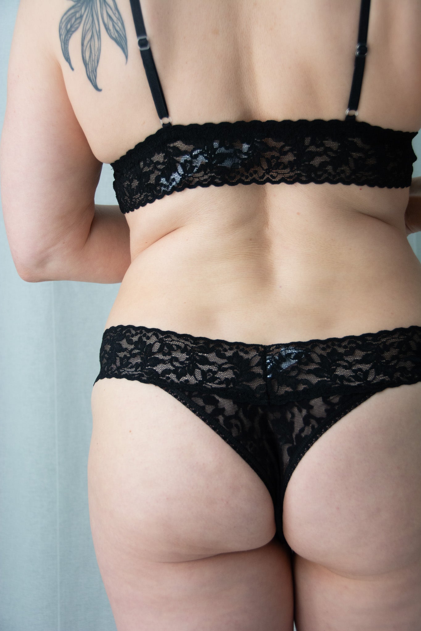 Person wearing black lace lingerie against a neutral background