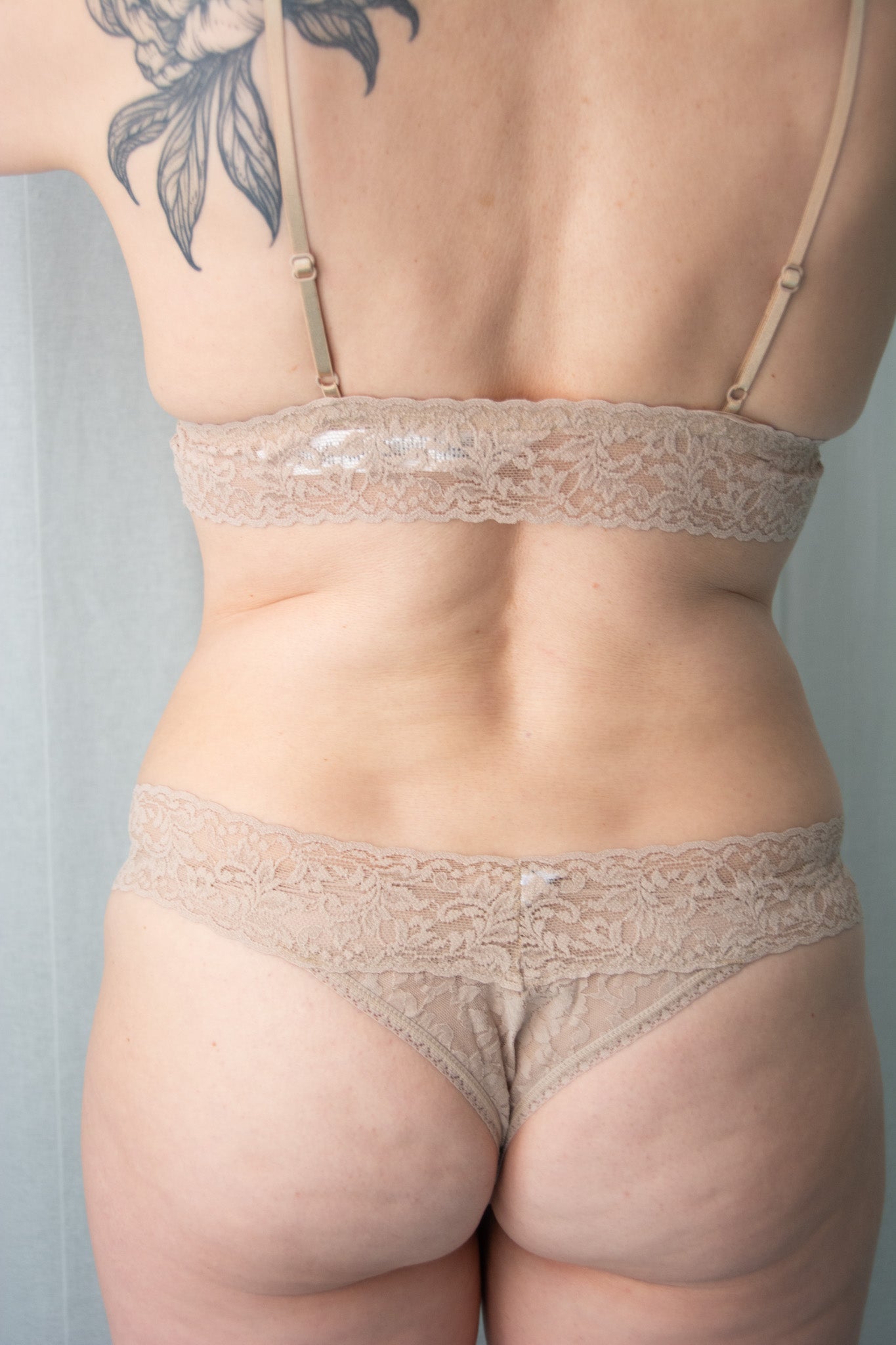 Person wearing beige lace lingerie against a neutral background