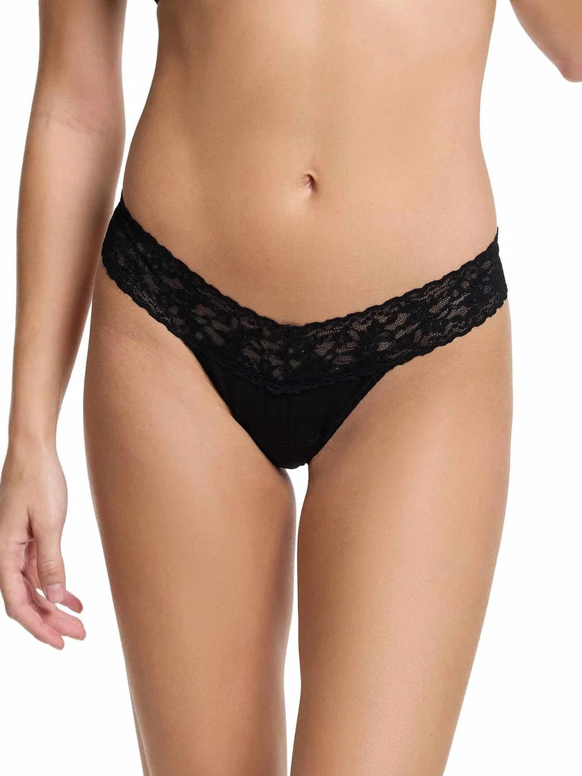 model wearing black lace thong against a white background