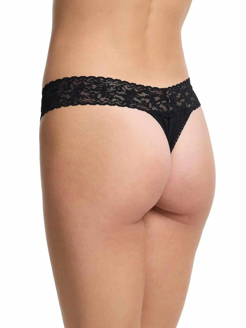 model wearing black lace thong against a white background