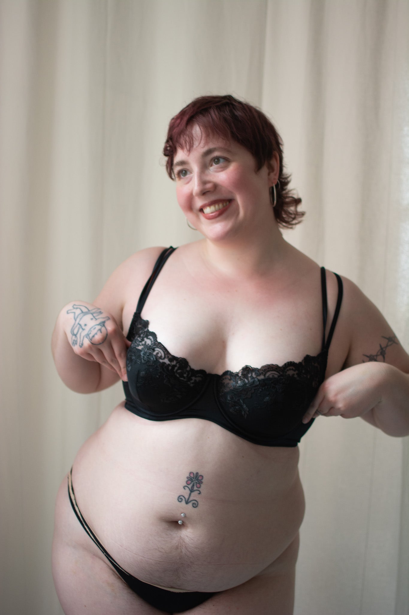 Person wearing black lace bra on neutral background.