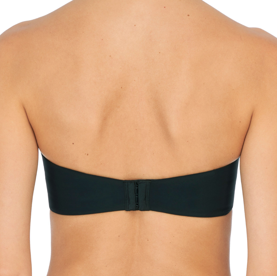 Person wearing black bra against a neutral background