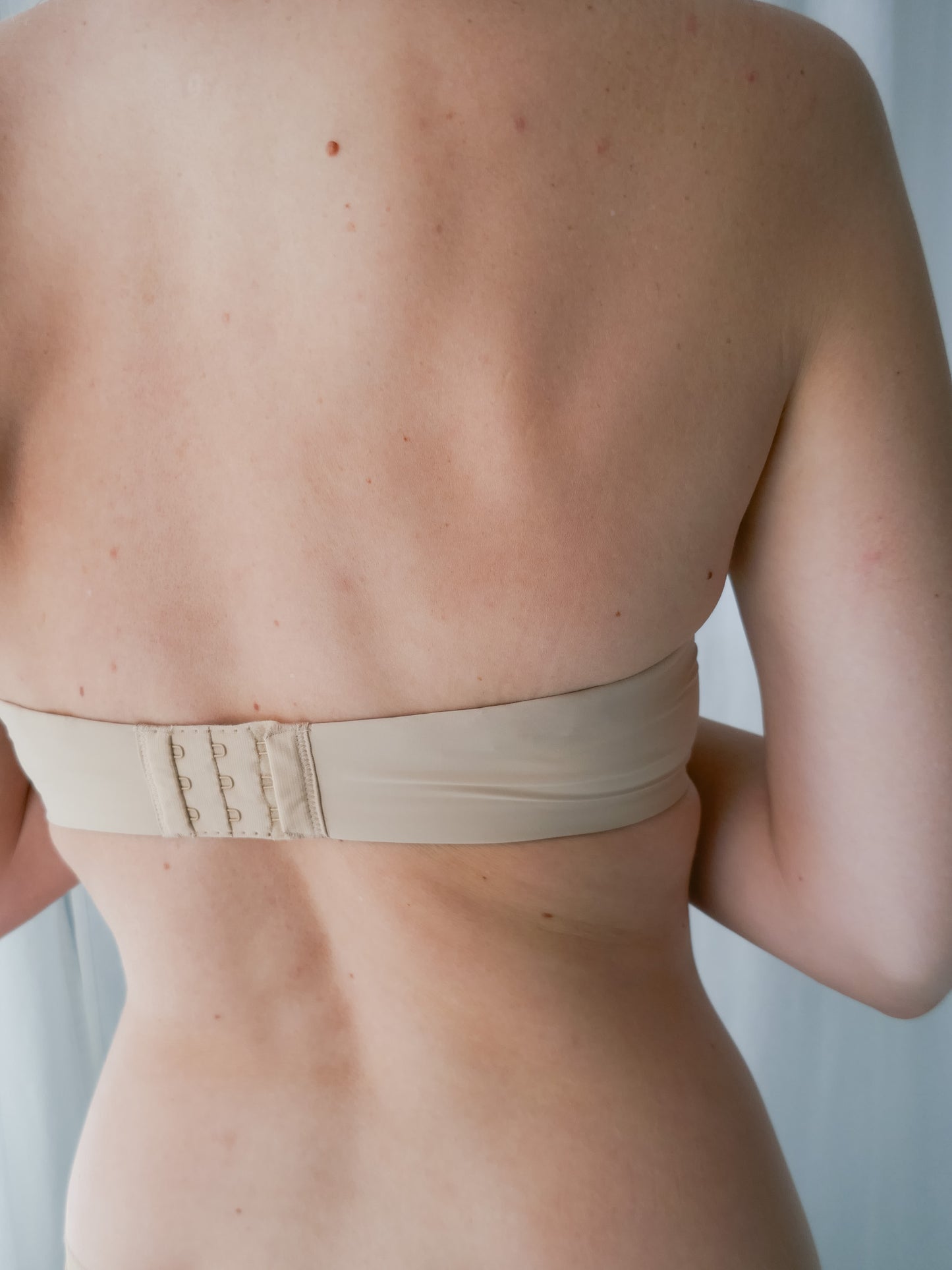 Beige bra worn by a person against a neutral background