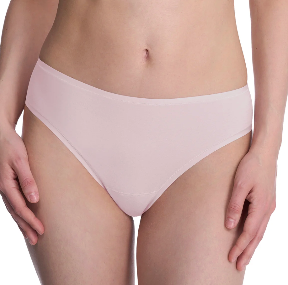 A close-up of a model wearing a pair of light pink seamless high-waisted briefs against a white background.
