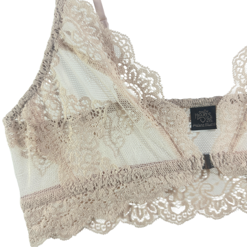 A close-up of a beige lace bra with sheer mesh panels and a black brand label reading 'HARPER&BAUMER'.