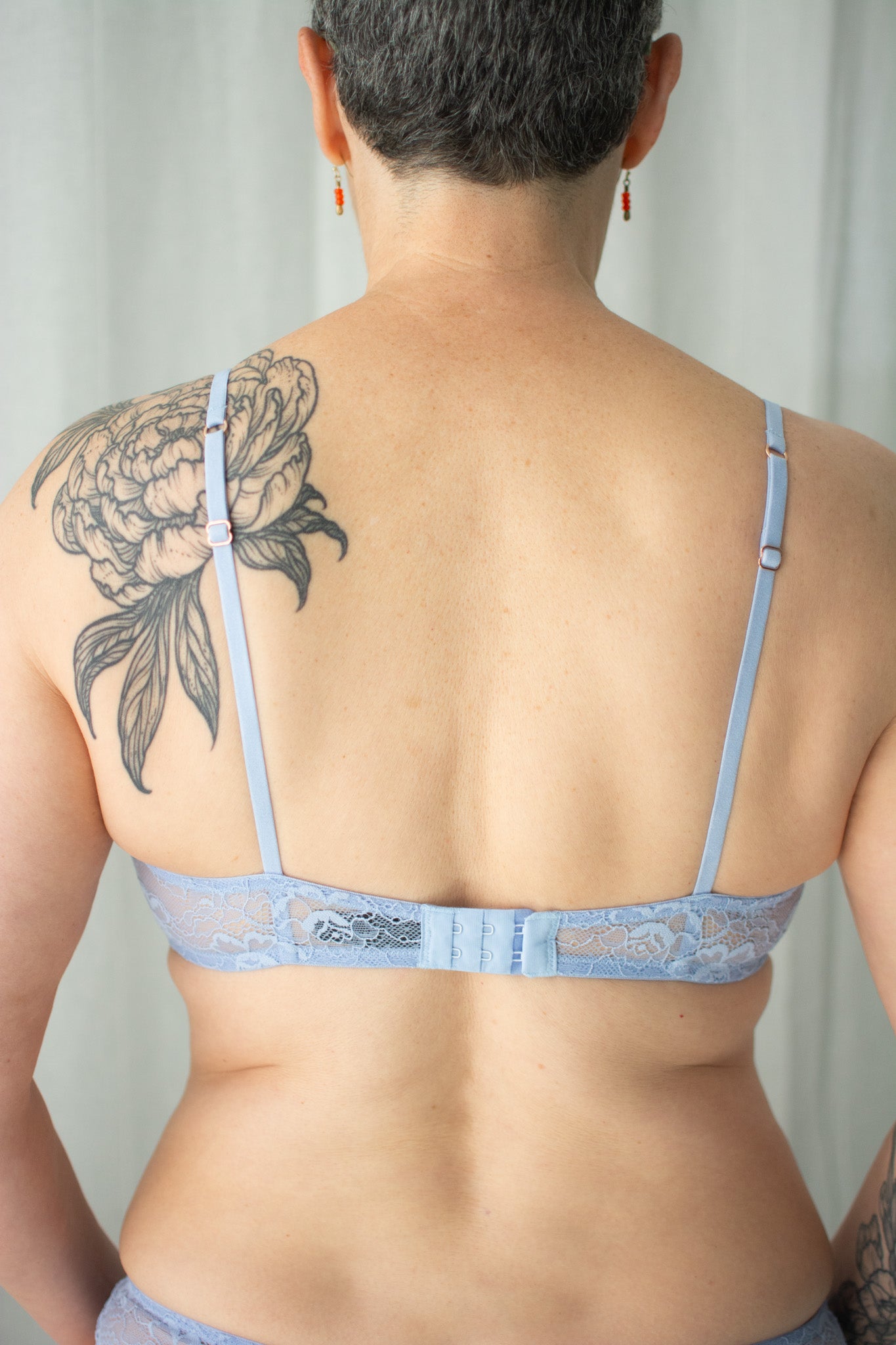 Person wearing a light blue lace bra with a neutral background