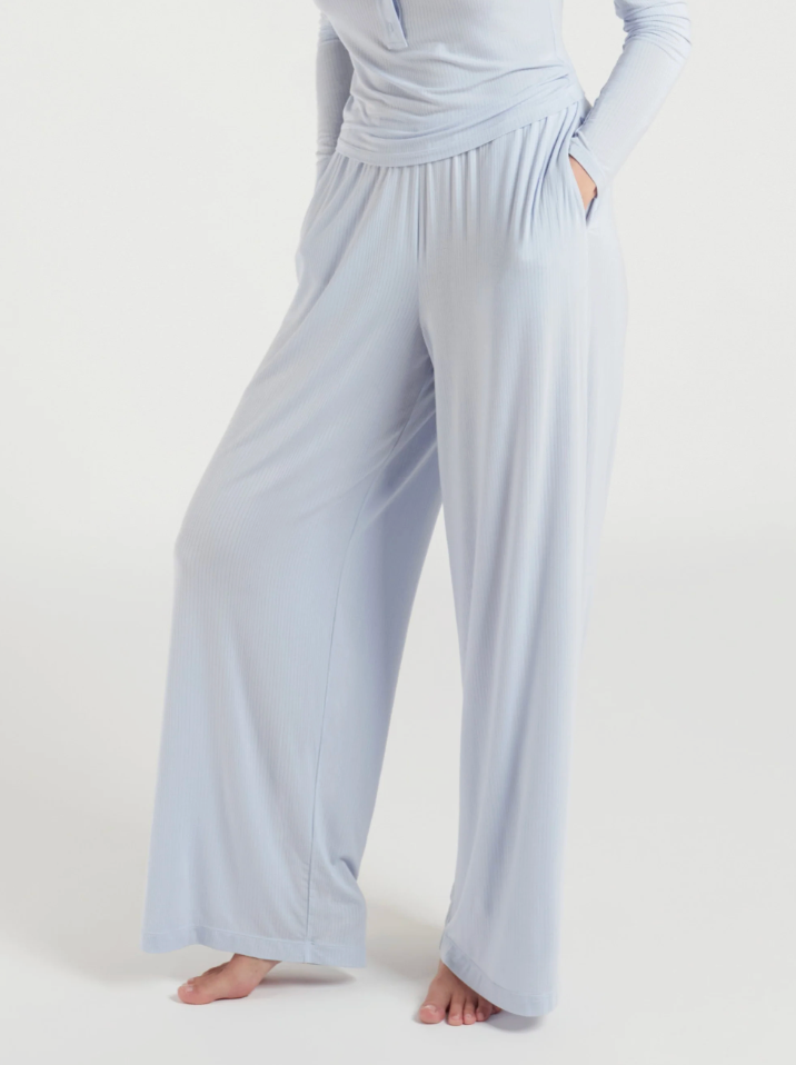 A person wearing light blue wide-leg lounge pants with a matching long-sleeve top, shown from the chest down against a plain light background.