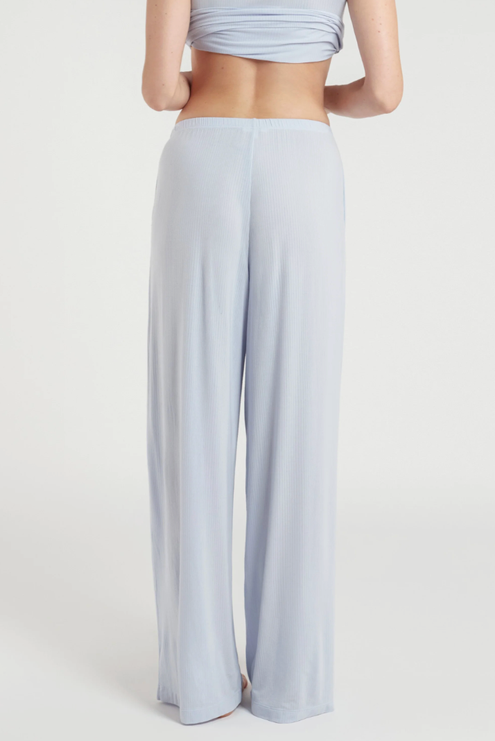 A model shown from the back wearing light blue wide-leg lounge pants and a matching light blue crop top against a plain light gray studio background.