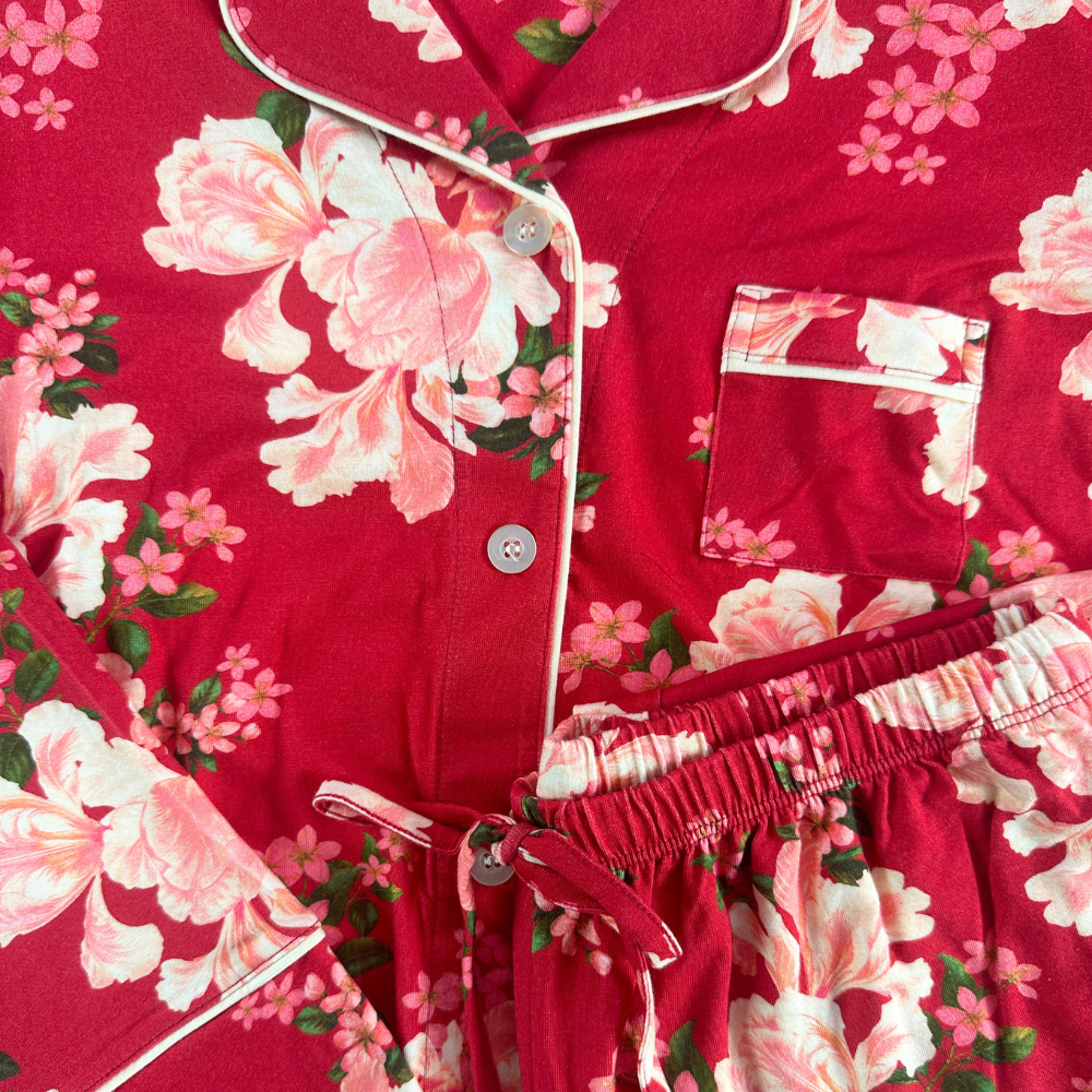 close up of red floral pajamas with buttons, a small side pocket and drawstring pants.