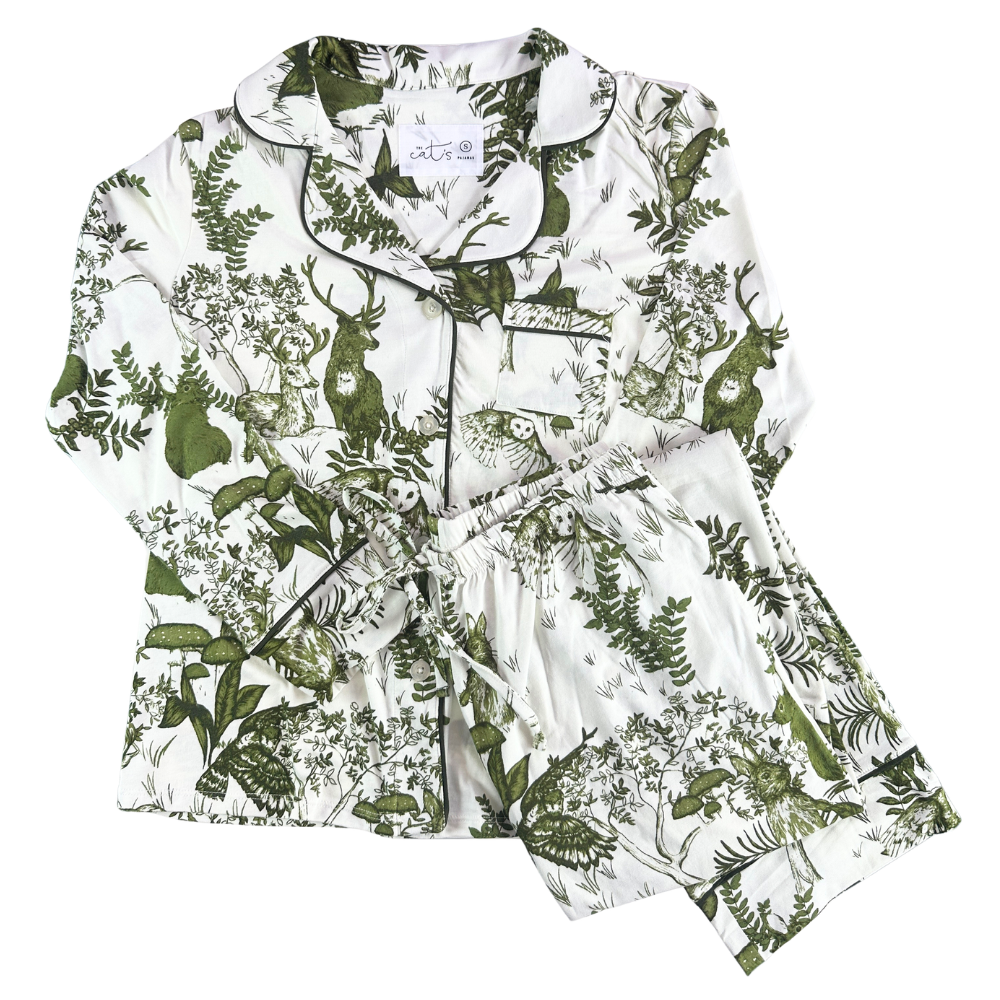 white pajamas with illustrations of woodland critters and fern against a white background.