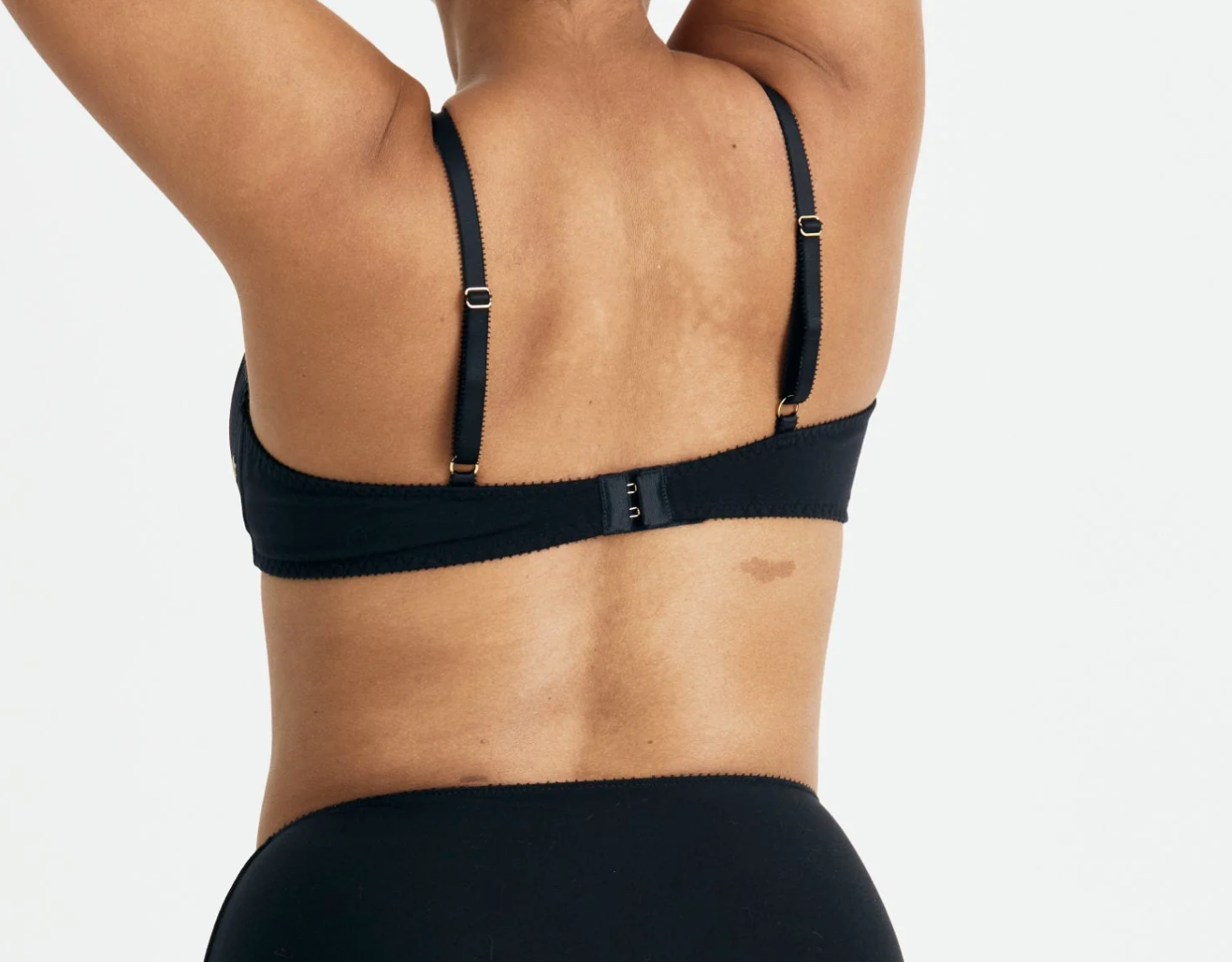Black bra worn by a person on a plain background