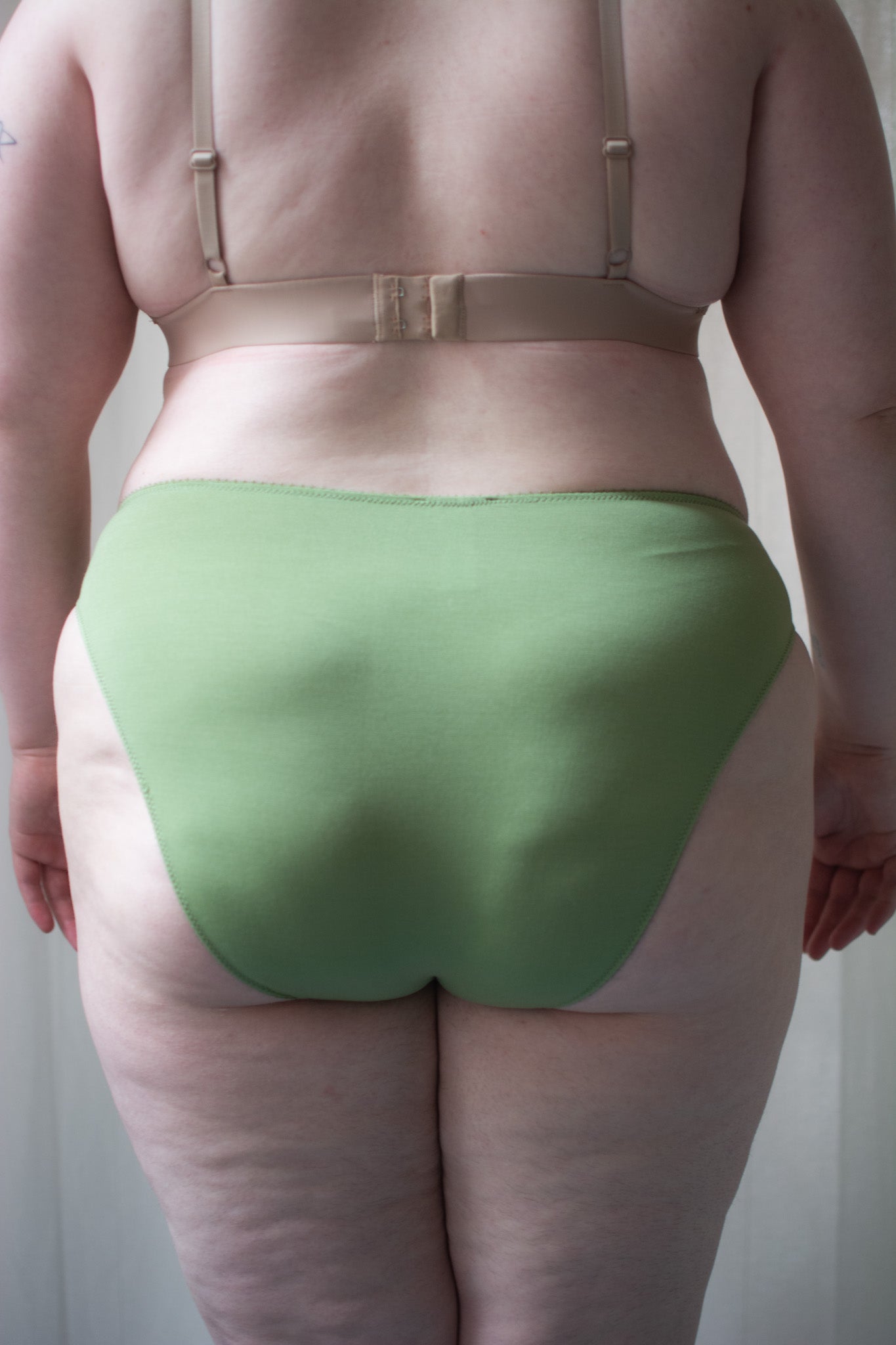 Person wearing green underwear against a neutral background.