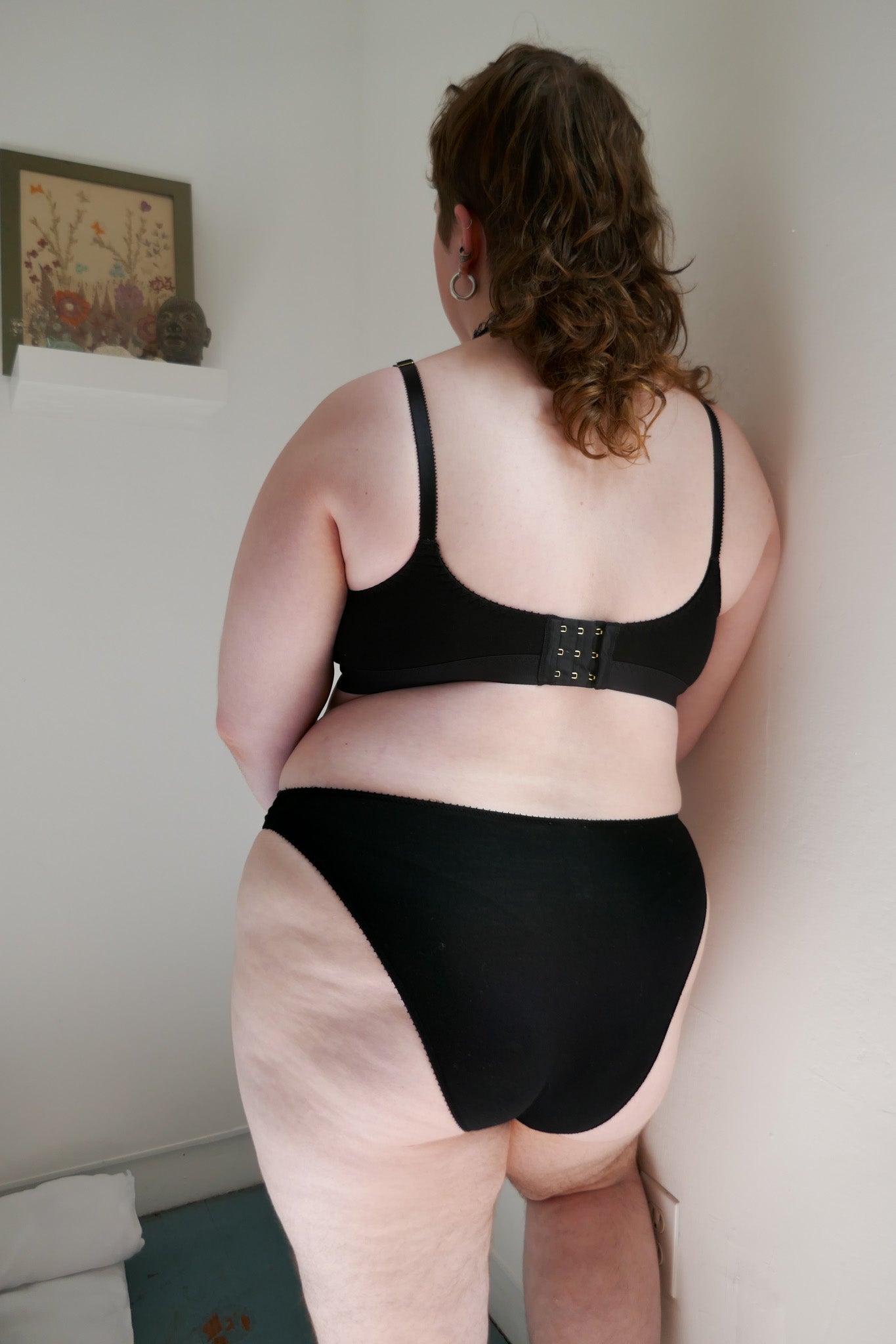 woman wearing black underwear and bra leaning on wall