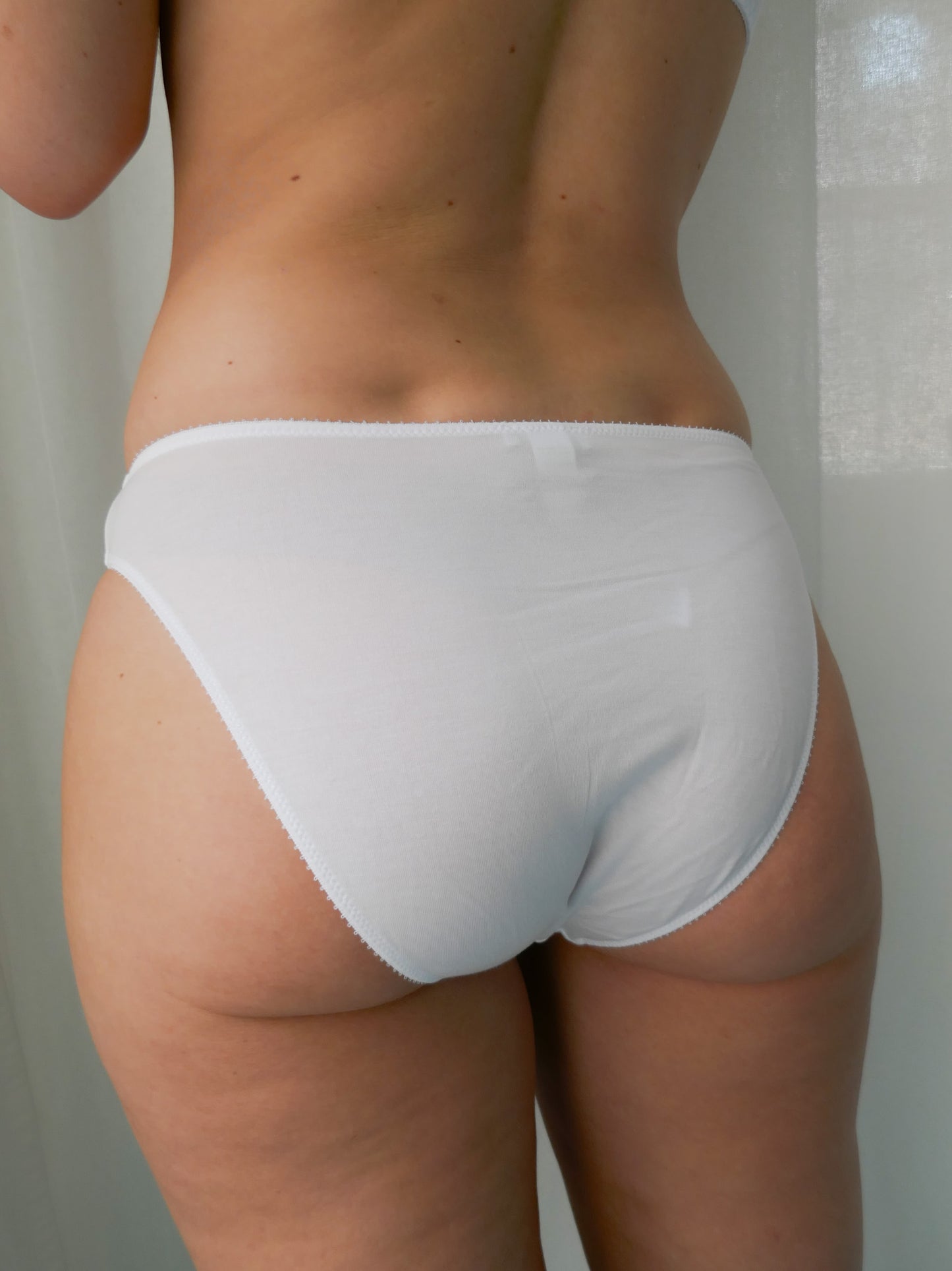 Person wearing a white underwear against a neutral background