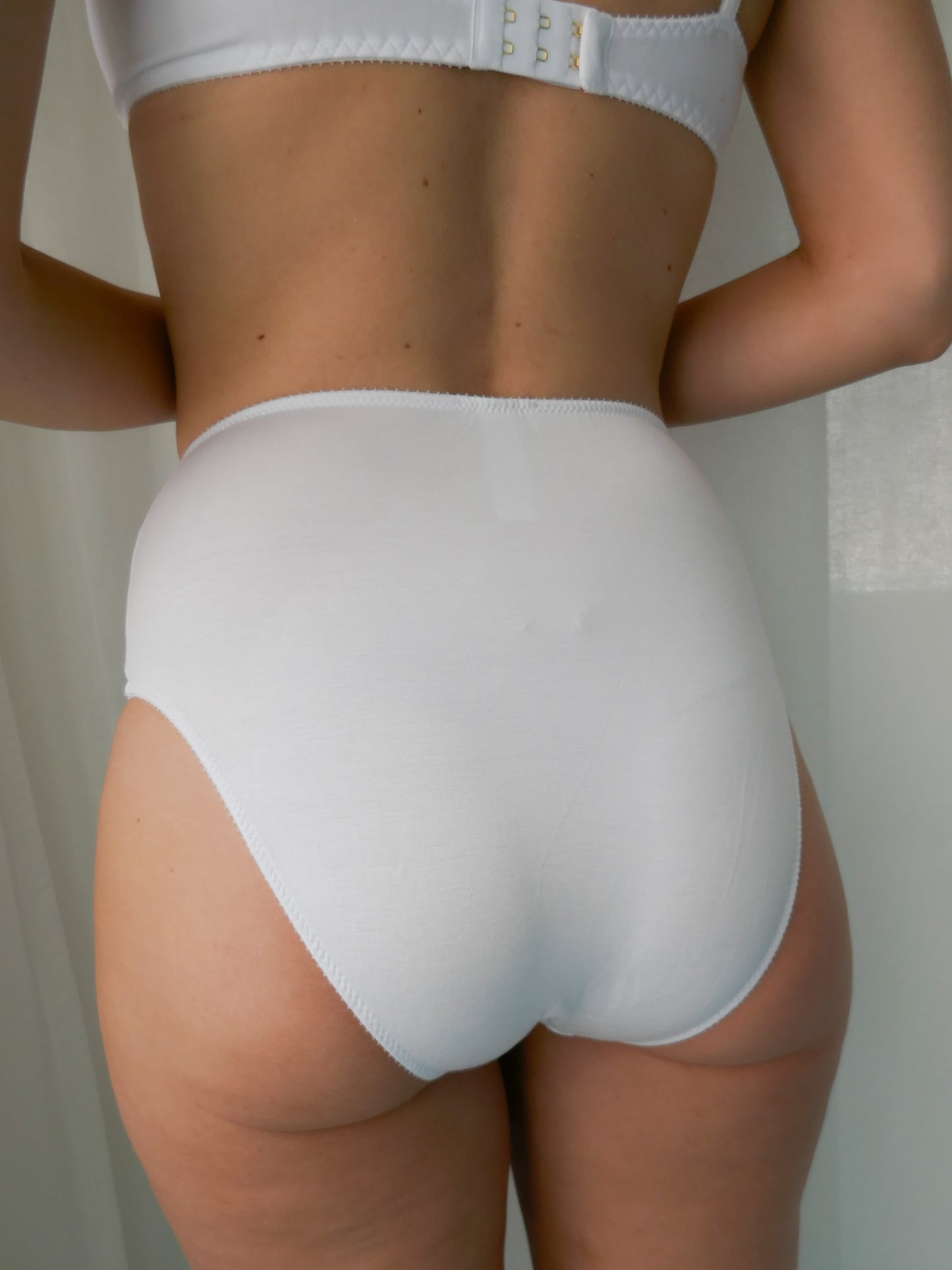 Person wearing white high-waisted underwear against a neutral background