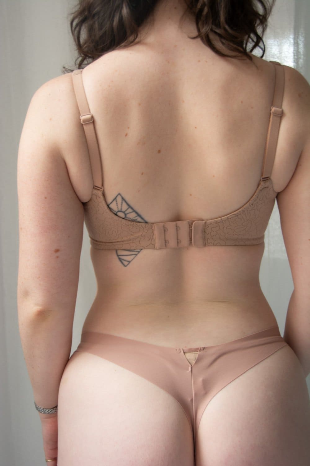Fleur du mal le stretch micro thong in tan, back view on a model, close-up.