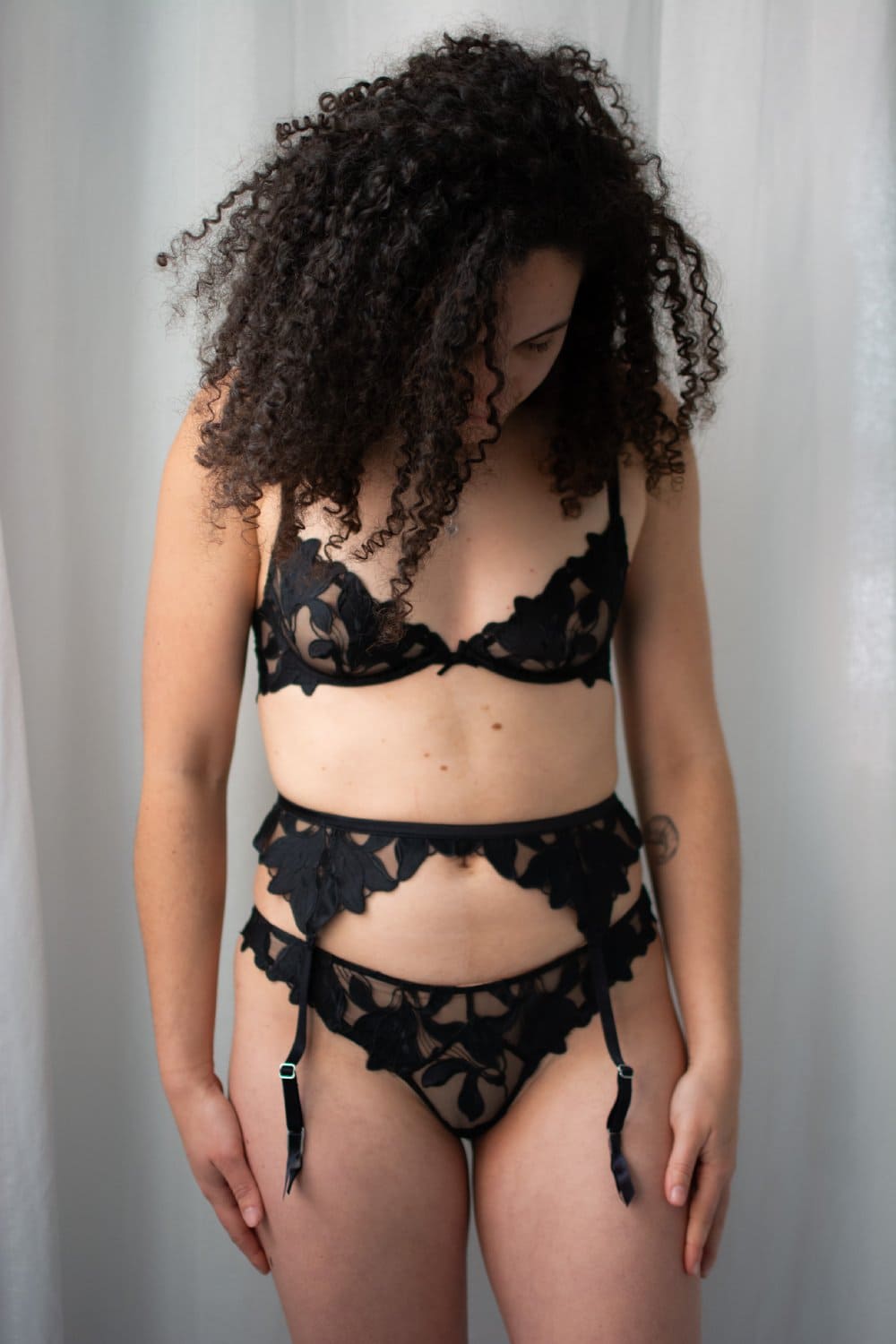 Fleur du mal lily lace garter belt in black, close-up front view on a model.