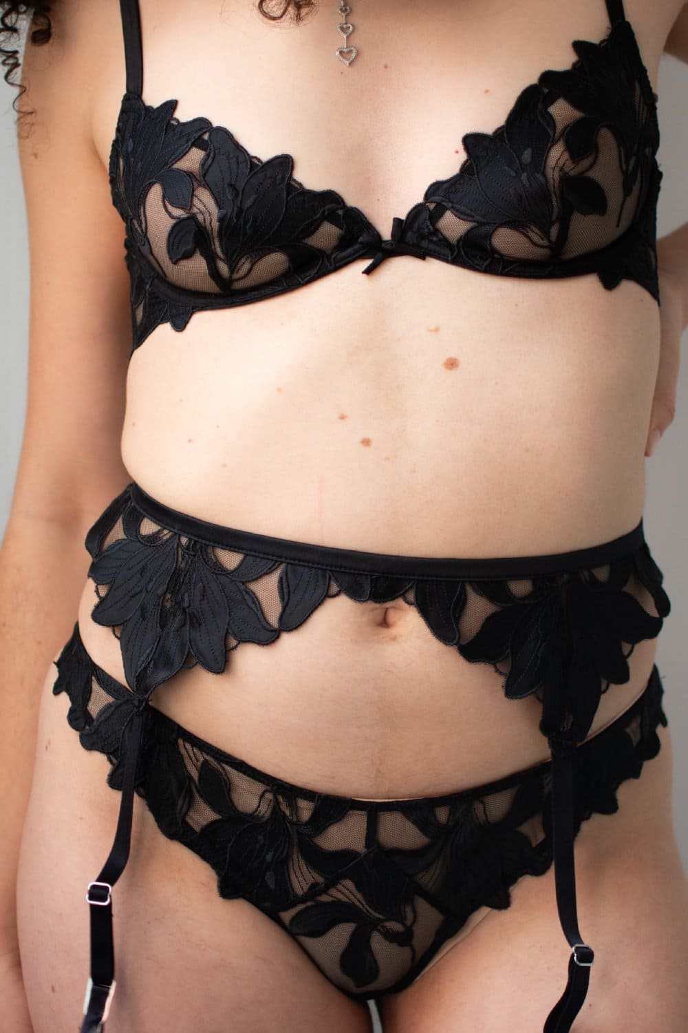 Fleur du mal lily lace garter belt in black, front view on a model, close-up.