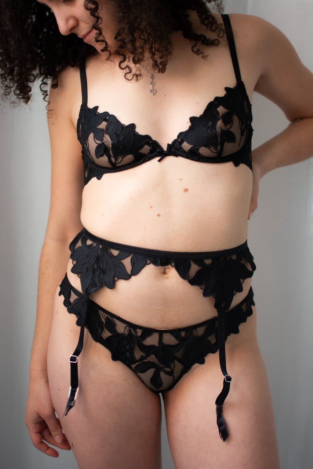 Fleur du mal lily lace garter belt in black, front view on a model.